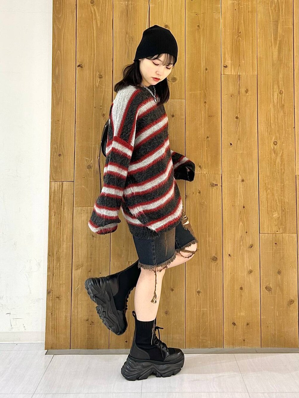 ブラック系のショルダーバッグ、ブラック系のブーツ、レッド系のニット/セーターを着用したレディースの秋コーディネートの4枚目の写真