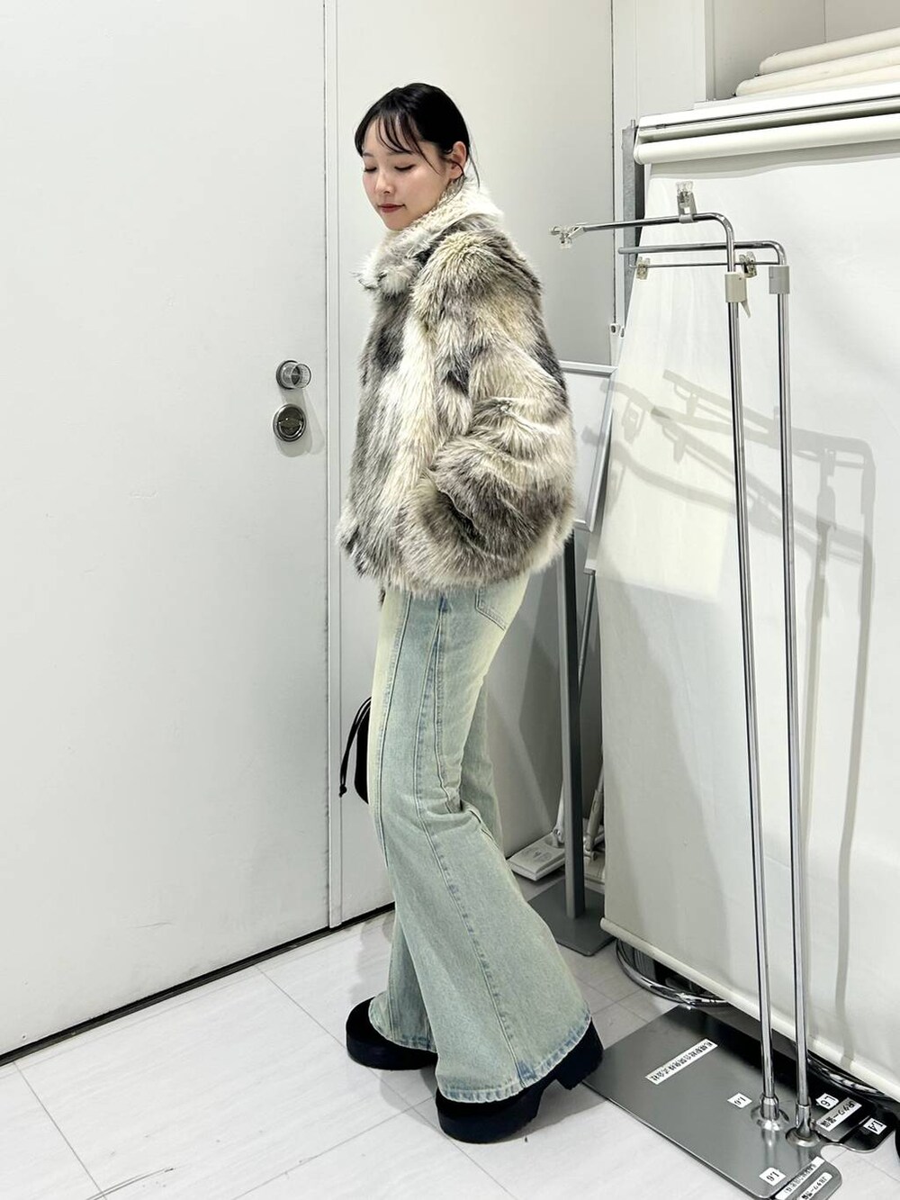 グレー系のブルゾン、ブルー系のデニムパンツ、ホワイト系のニット/セーターを着用したレディースの冬コーディネートの2枚目の写真