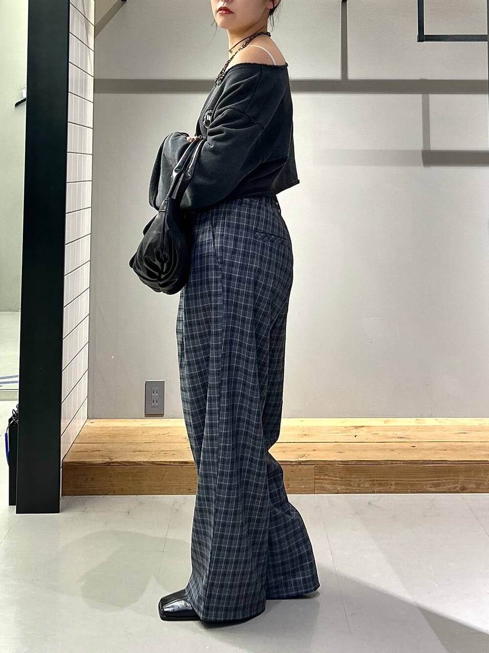 ブラック系のブーツ、グレー系のスラックス、ブラック系のハンドバッグを着用したレディースの秋コーディネートの6枚目の写真