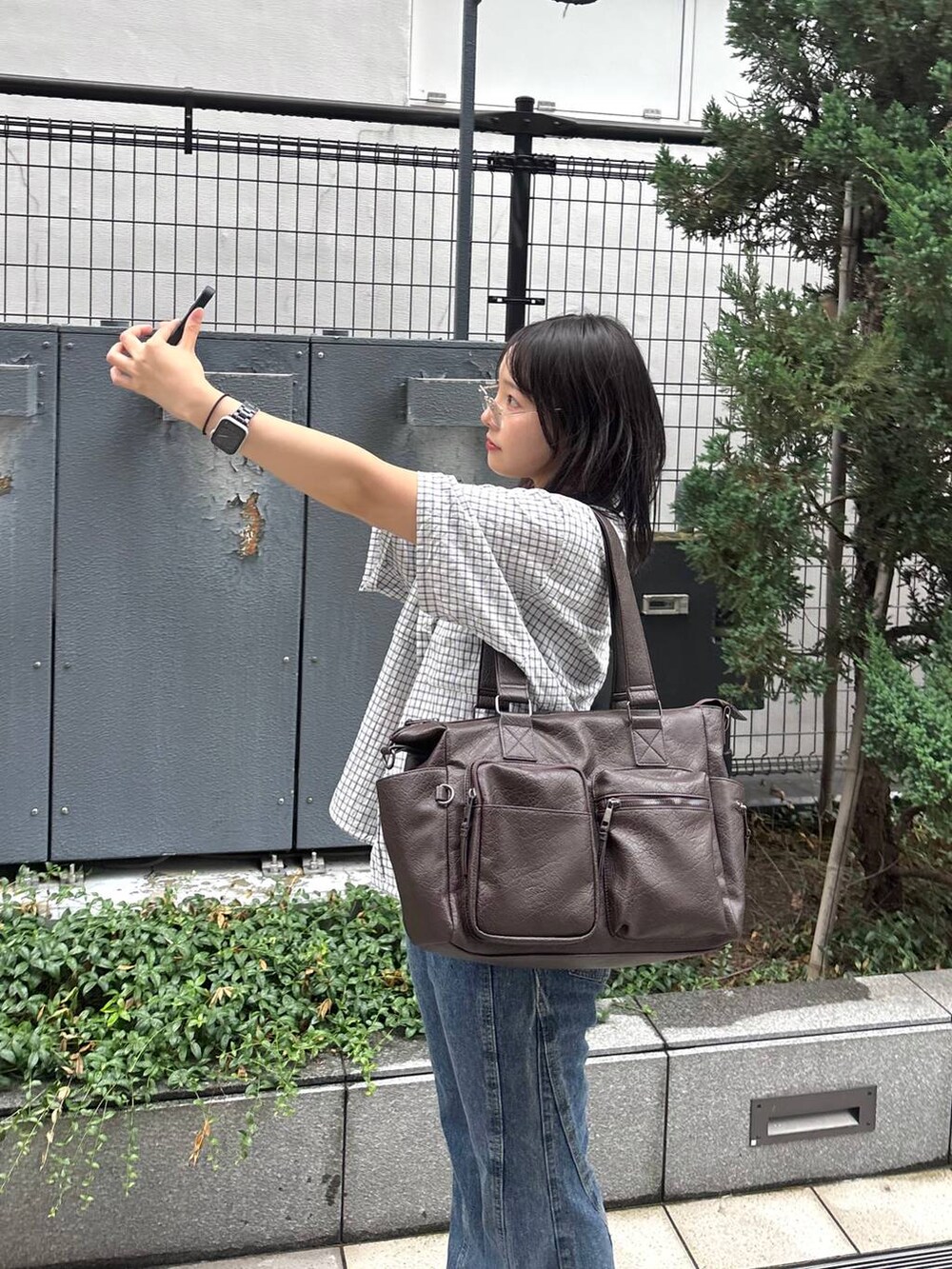 ブルー系のデニムパンツ、ホワイト系のシャツ/ブラウス、ブラック系のボストンバッグを着用したレディースの夏コーディネートの4枚目の写真