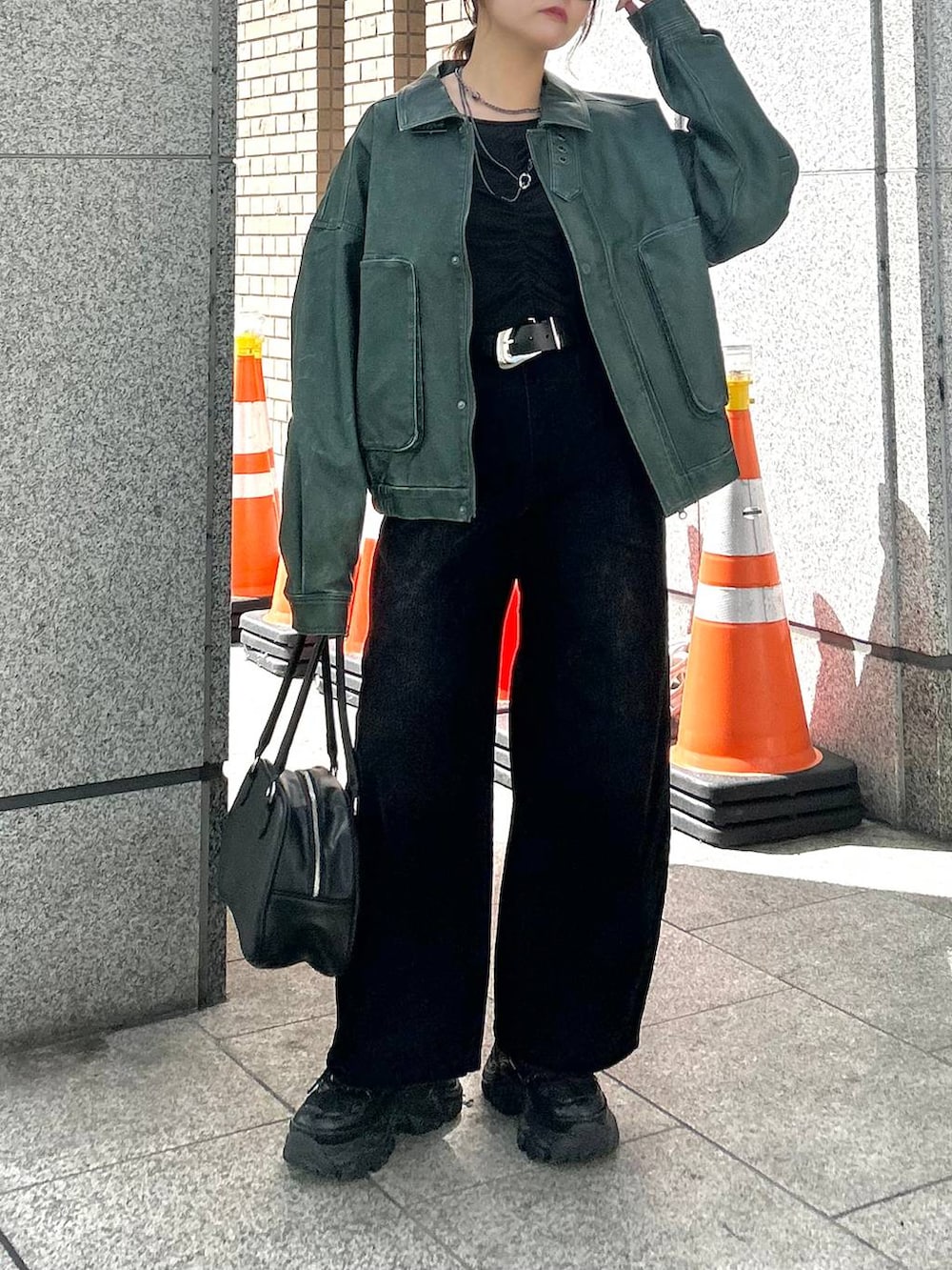 ブラック系のスニーカー、ブラック系のデニムパンツ、グリーン系のブルゾンを着用したレディースの秋コーディネートの2枚目の写真