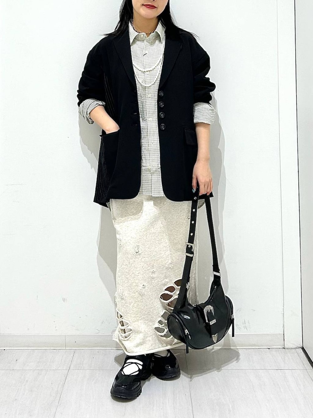 ブラック系のスニーカー、ブラック系のテーラードジャケット、ブラック系のショルダーバッグを着用したレディースの春コーディネートの3枚目の写真
