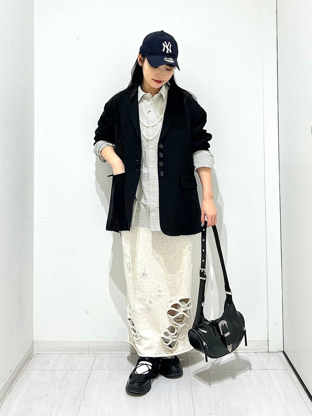 ブラック系のスニーカー、ブラック系のテーラードジャケット、ブラック系のショルダーバッグを着用したレディースの春コーディネートの2枚目の写真