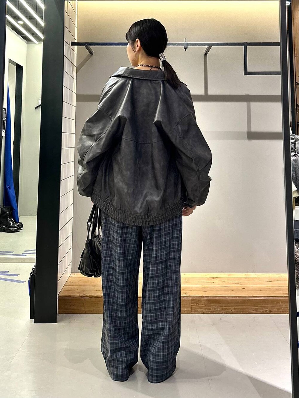 グレー系のブルゾン、ブラック系のブーツ、グレー系のスラックスを着用したレディースの秋コーディネートの5枚目の写真