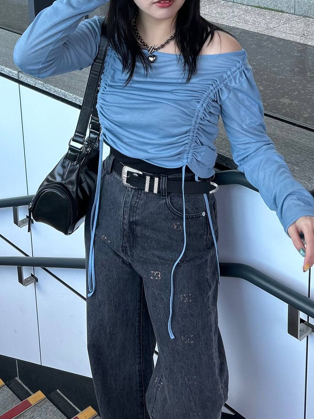 ブラック系のデニムパンツ、ブラック系のスニーカー、ブラック系のショルダーバッグを着用したレディースの春コーディネートの2枚目の写真