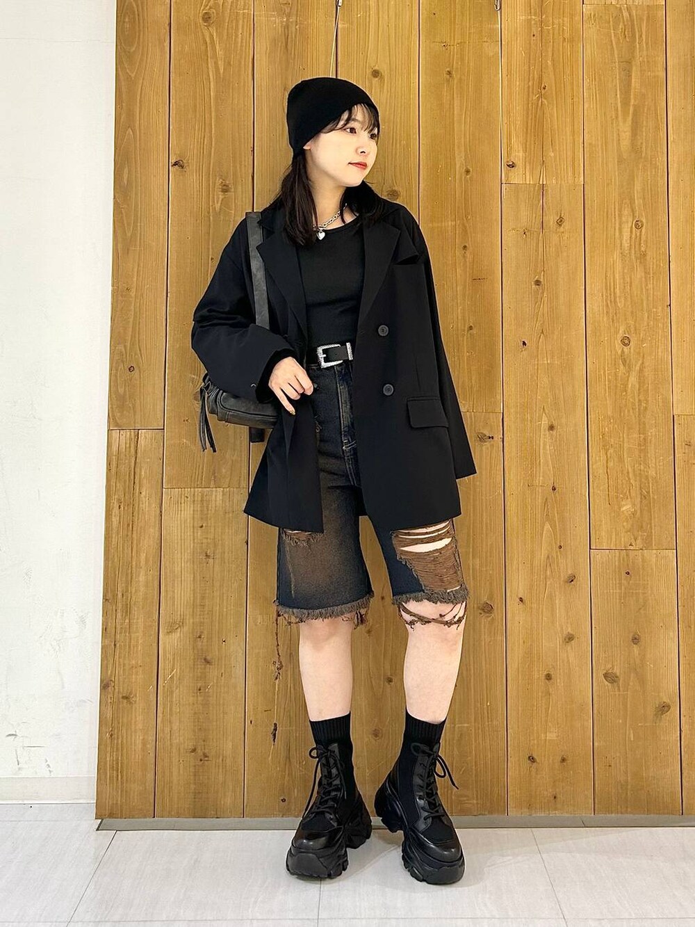 ブラック系のテーラードジャケット、ブラック系のショルダーバッグ、ブラック系のブーツを着用したレディースの秋コーディネートの2枚目の写真