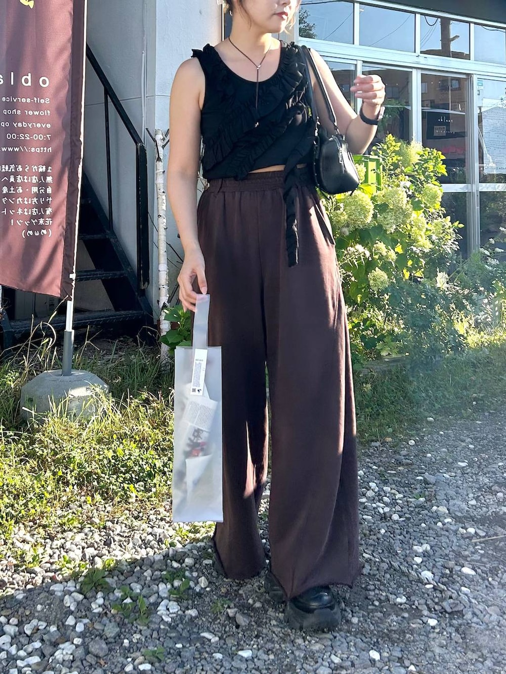 ブラック系のスニーカー、ブラック系のボストンバッグ、ブラウン系のスウェットパンツを着用したレディースの夏コーディネートの2枚目の写真