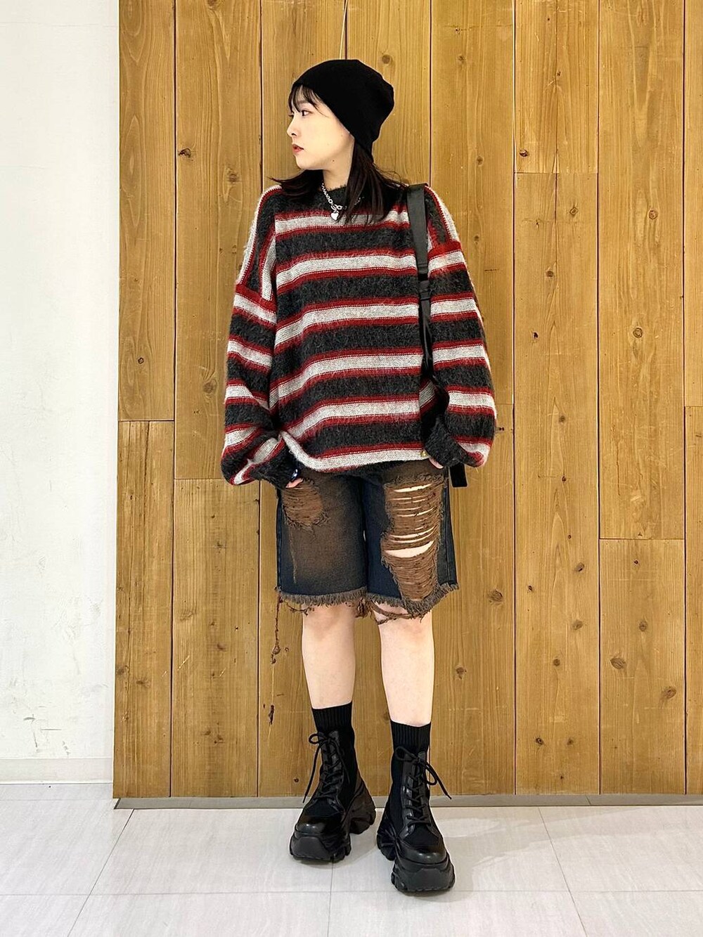 ブラック系のショルダーバッグ、ブラック系のブーツ、レッド系のニット/セーターを着用したレディースの秋コーディネートの2枚目の写真