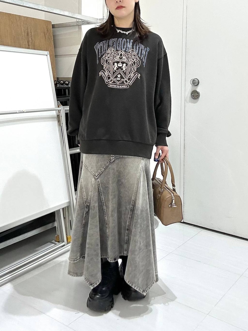 ブラック系のブーツ、グレー系のスウェット、ブラウン系のボストンバッグを着用したレディースの冬コーディネートの3枚目の写真