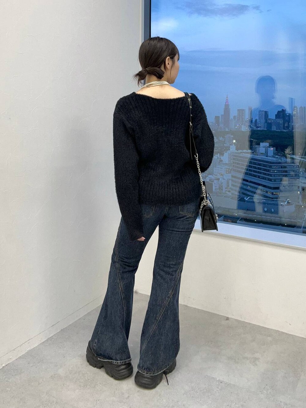 ブラック系のスニーカー、ブルー系のデニムパンツ、ブラック系のニット/セーターを着用したレディースの秋コーディネートの6枚目の写真