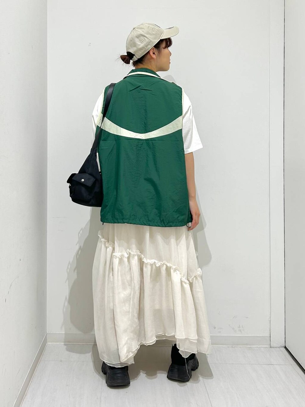 グリーン系のベスト、ホワイト系のスカート、ホワイト系のTシャツ/カットソーを着用したレディースの春コーディネートの6枚目の写真