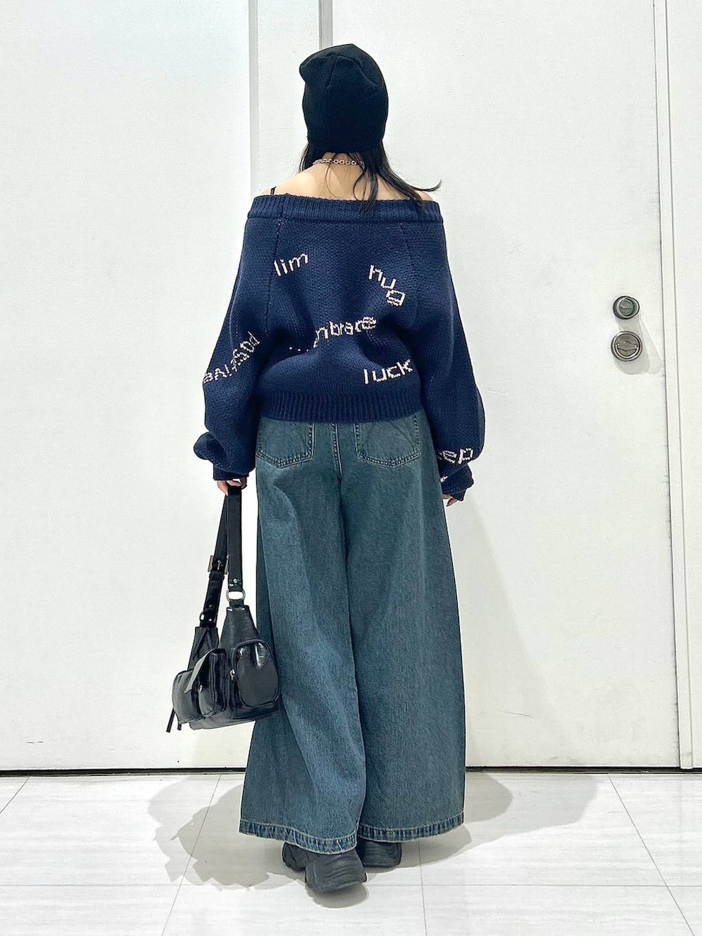 ブルー系のデニムパンツ、ブラック系のショルダーバッグ、ブルー系のニット/セーターを着用したレディースの秋コーディネートの4枚目の写真