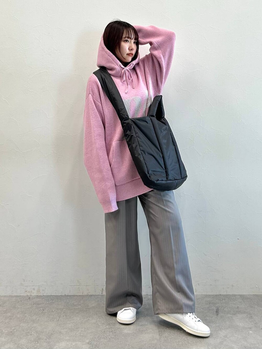 グレー系のスラックス、ブラック系のトートバッグ、ピンク系のニット/セーターを着用したレディースの冬コーディネートの2枚目の写真