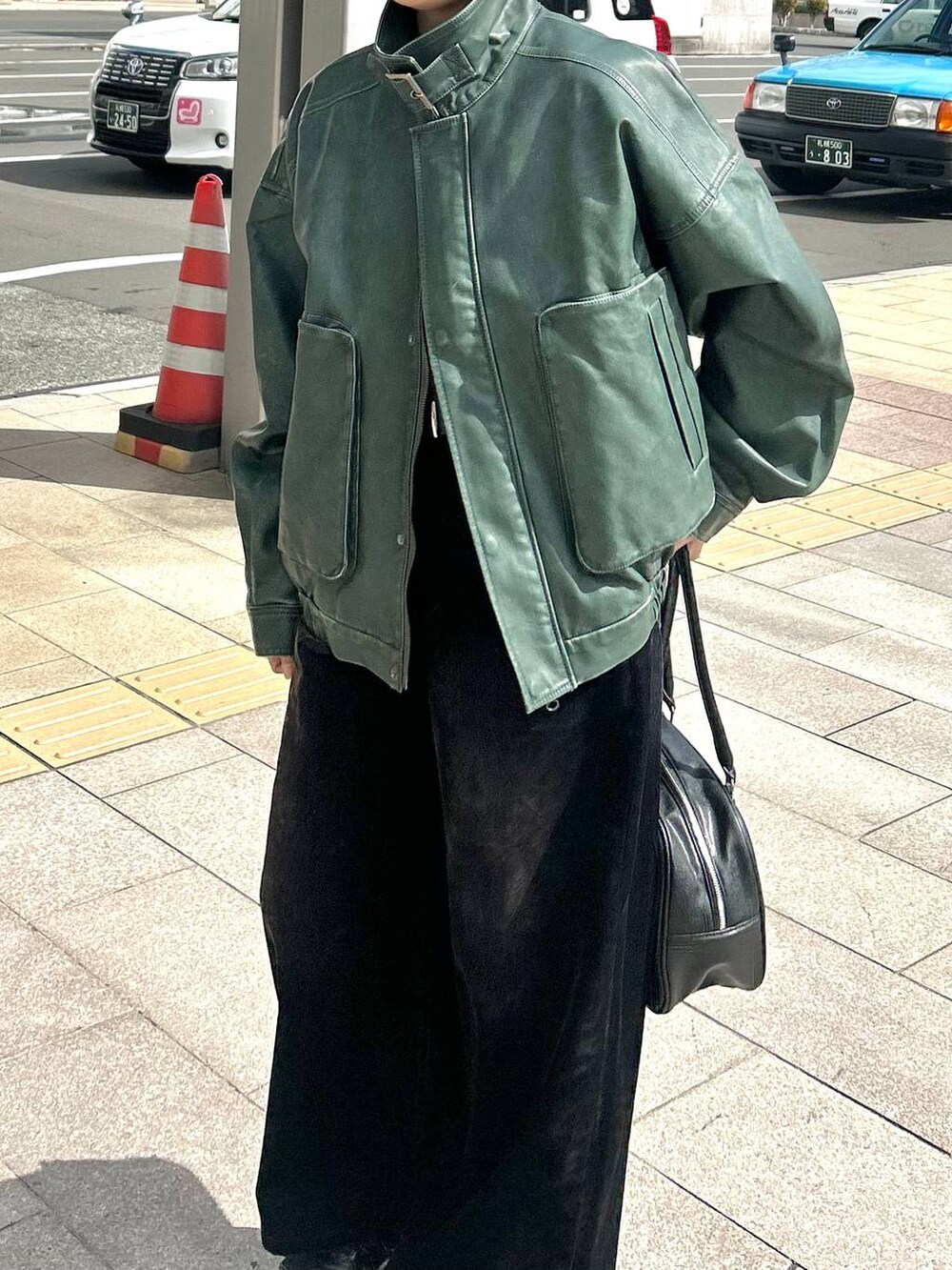 ブラック系のデニムパンツ、グリーン系のブルゾンを着用したレディースの秋コーディネートの2枚目の写真