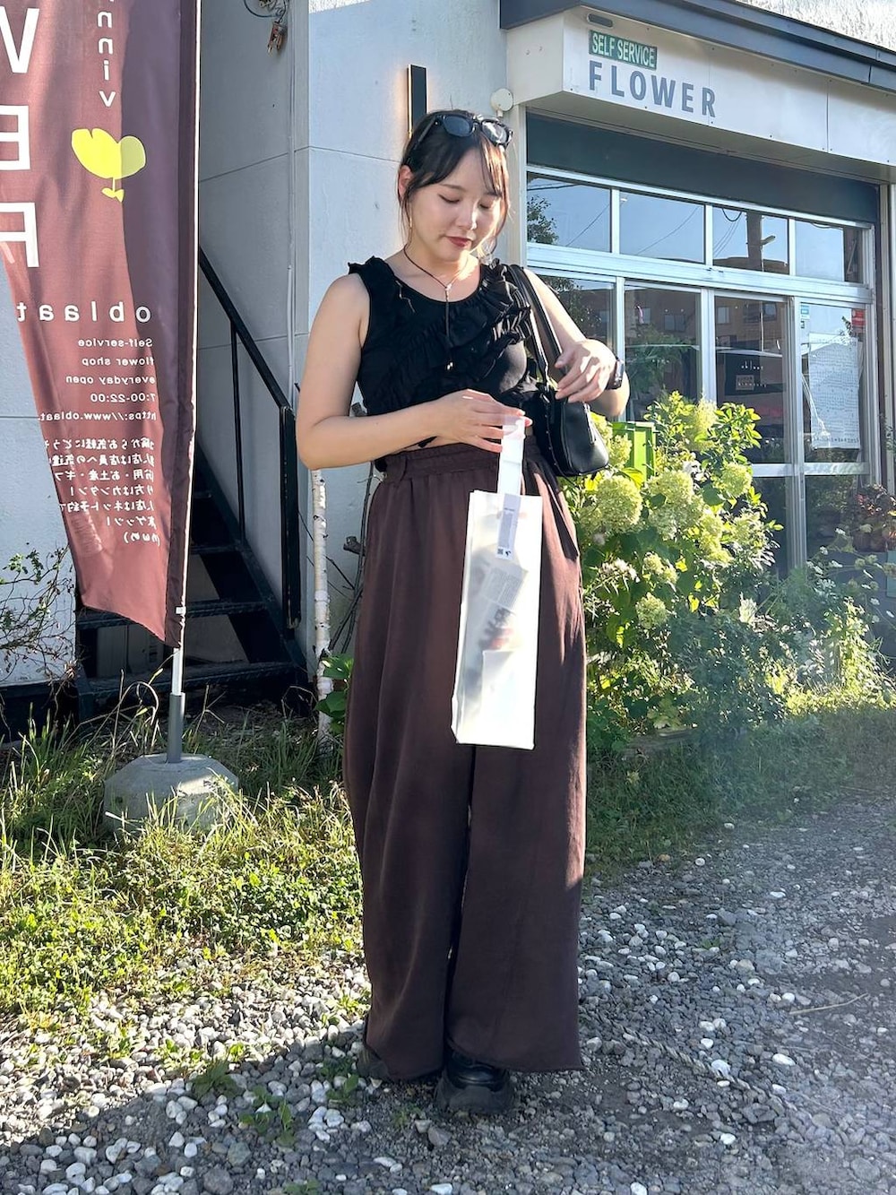 ブラック系のスニーカー、ブラック系のボストンバッグ、ブラウン系のスウェットパンツを着用したレディースの夏コーディネートの3枚目の写真