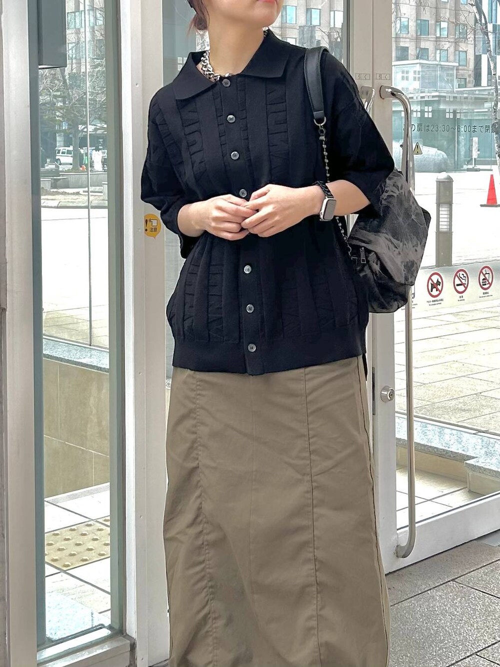 ブラック系のショルダーバッグ、グリーン系のスカート、ブラック系のニット/セーターを着用したレディースの春コーディネートの3枚目の写真