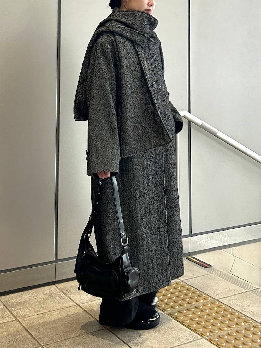 ブラック系のチェスターコート、ブラック系のスラックス、ブラック系のショルダーバッグを着用したレディースの冬コーディネートの5枚目の写真