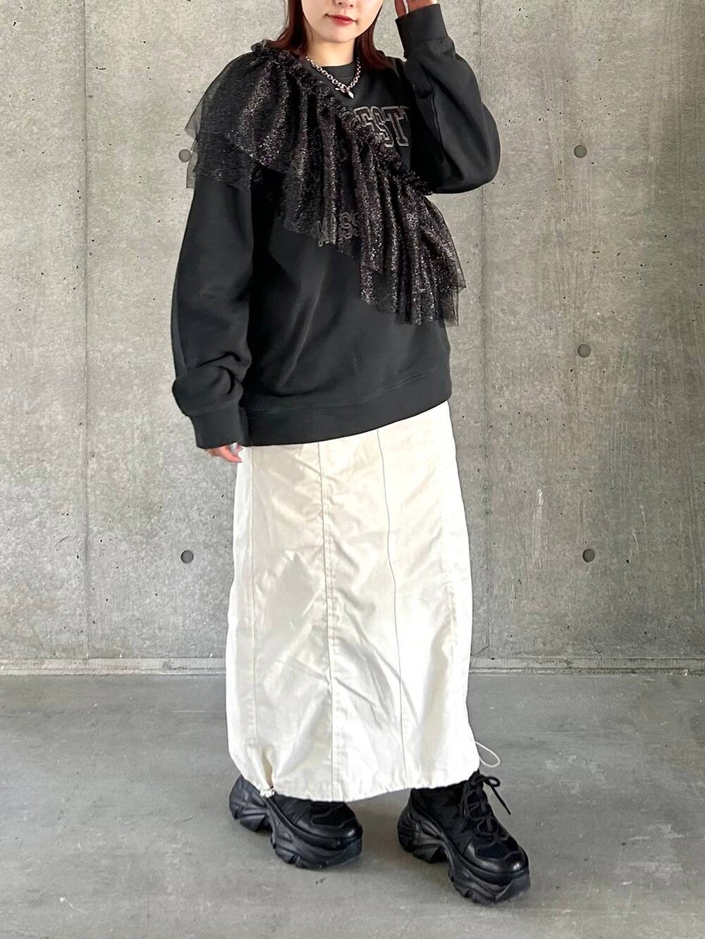 ブラック系のスニーカー、ホワイト系のスカート、ブラック系のスウェットを着用したレディースの春コーディネートの5枚目の写真