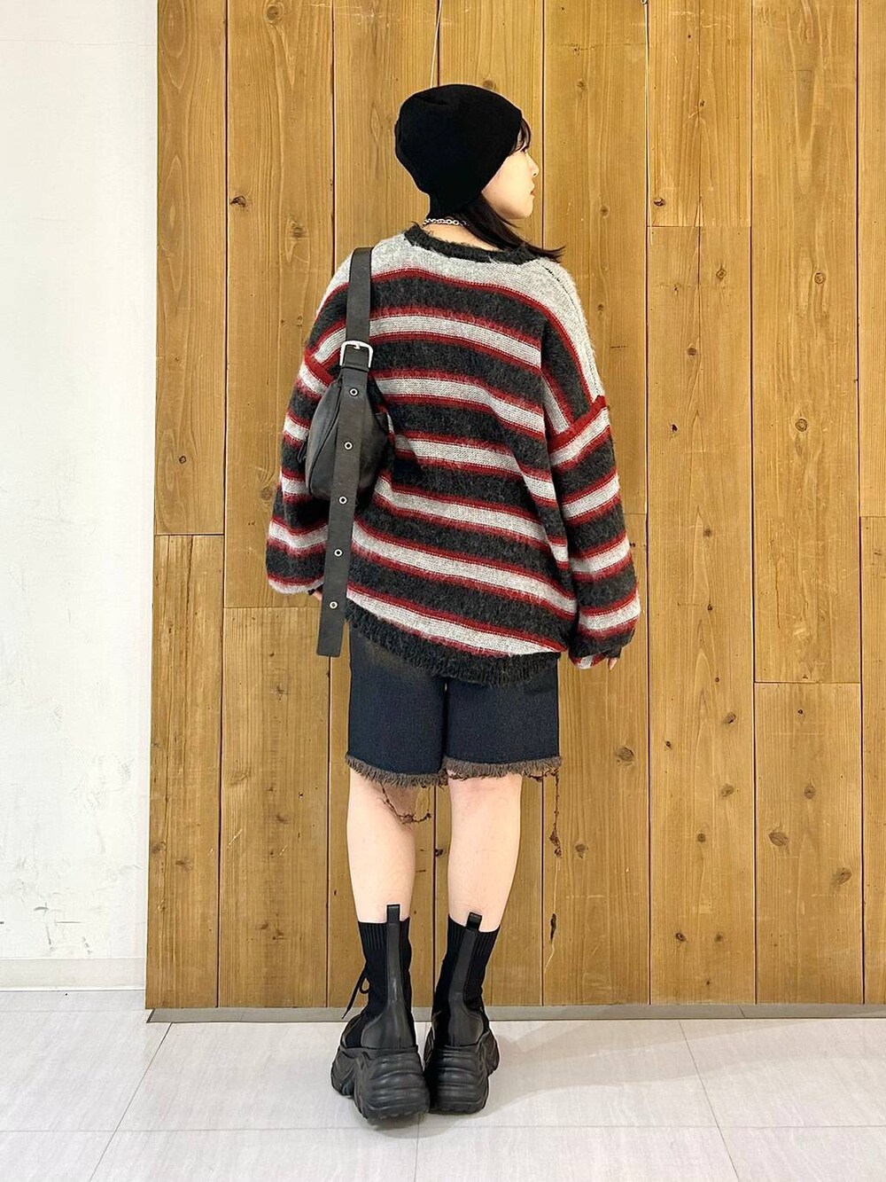 ブラック系のショルダーバッグ、ブラック系のブーツ、レッド系のニット/セーターを着用したレディースの秋コーディネートの6枚目の写真