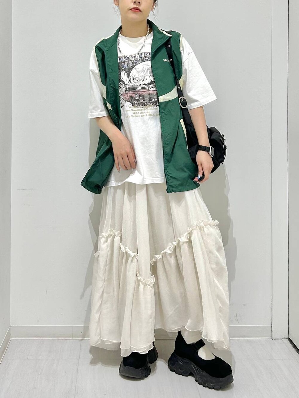 グリーン系のベスト、ホワイト系のスカート、ホワイト系のTシャツ/カットソーを着用したレディースの春コーディネートの3枚目の写真