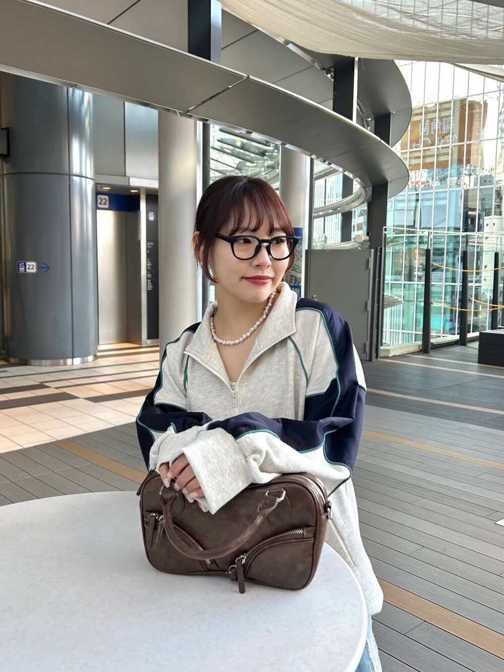 ブルー系のデニムパンツ、ブラウン系のボストンバッグ、ベージュ系のスウェットを着用したレディースの冬コーディネートの4枚目の写真