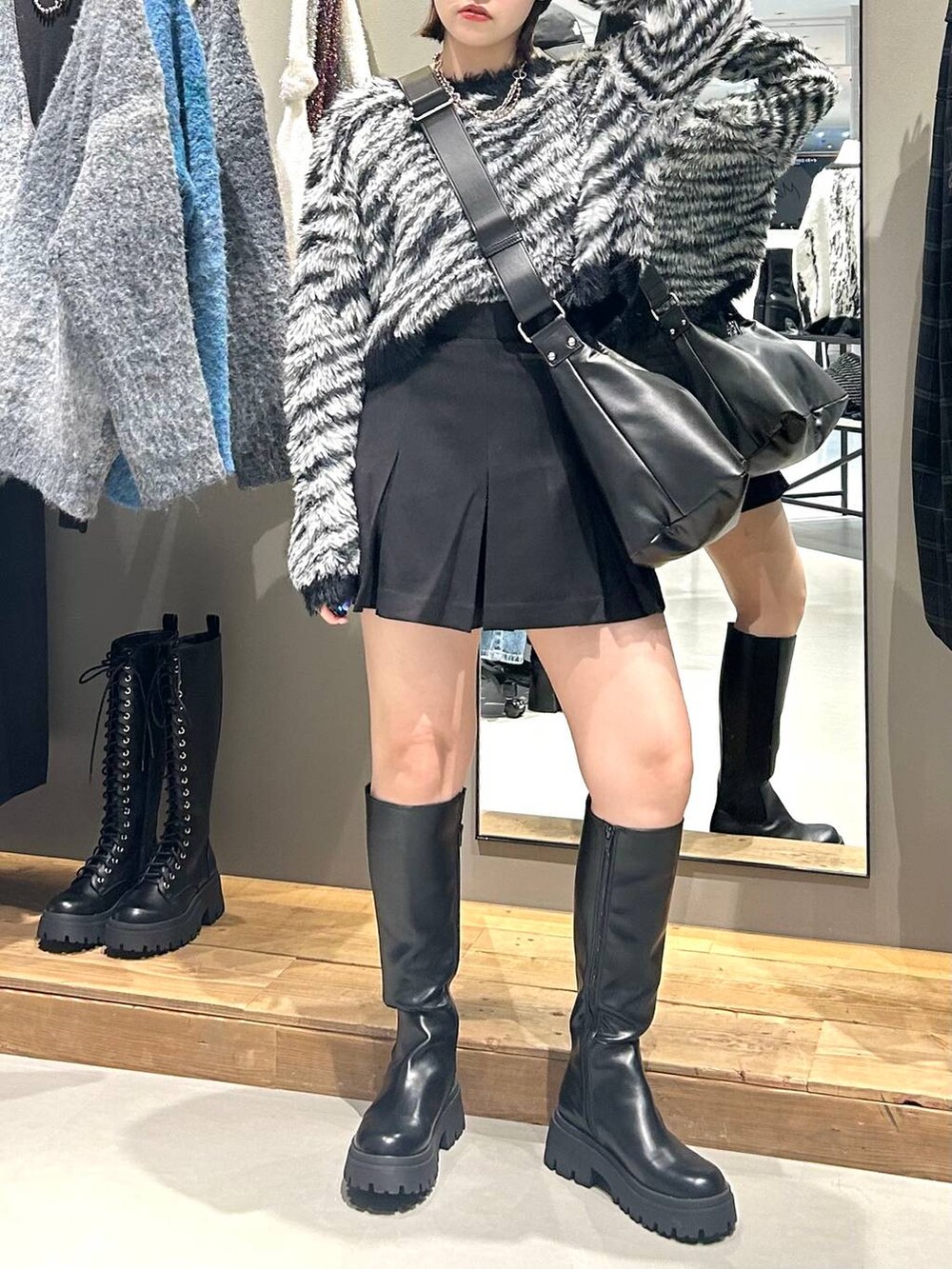 ブラック系のブーツ、ブラック系のショルダーバッグ、その他のカーディガン/ボレロを着用したレディースの秋コーディネートの5枚目の写真