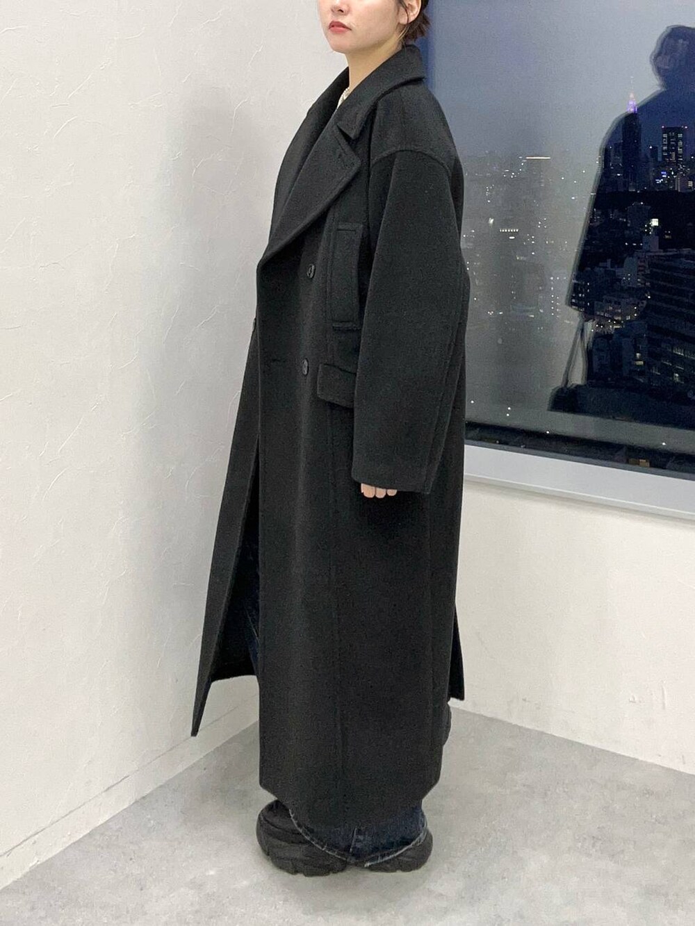 ブラック系のスニーカー、ブルー系のデニムパンツ、ブラック系のチェスターコートを着用したレディースの秋コーディネートの4枚目の写真