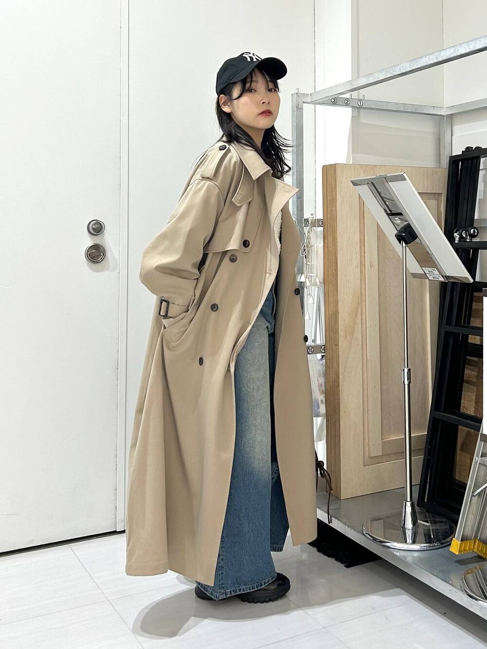 ブルー系のデニムパンツ、ブラウン系のショルダーバッグ、ベージュ系のトレンチコートを着用したレディースの冬コーディネートの3枚目の写真