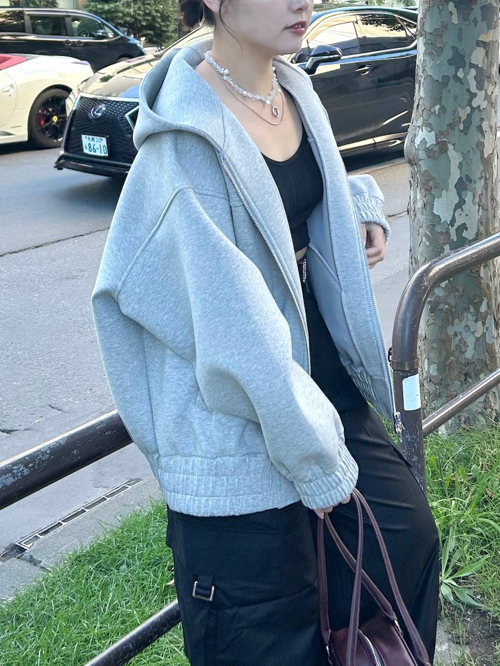 グレー系のパーカー、レッド系のボストンバッグ、ブラック系のスラックスを着用したレディースの秋コーディネートの2枚目の写真