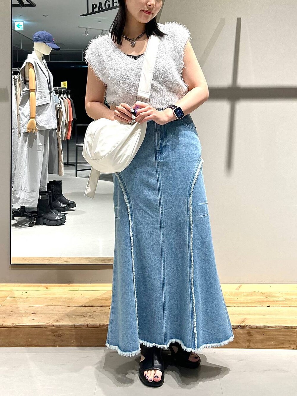 ホワイト系のベスト、ブルー系のデニムスカート、ブラック系のネックレスを着用したレディースの夏コーディネートの2枚目の写真