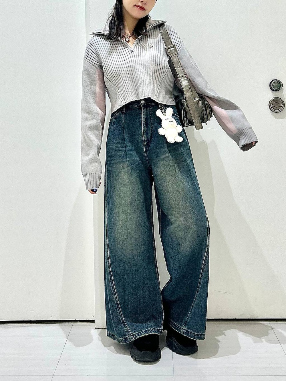 ブルー系のデニムパンツ、グレー系のショルダーバッグ、グレー系のニット/セーターを着用したレディースの秋コーディネートの3枚目の写真