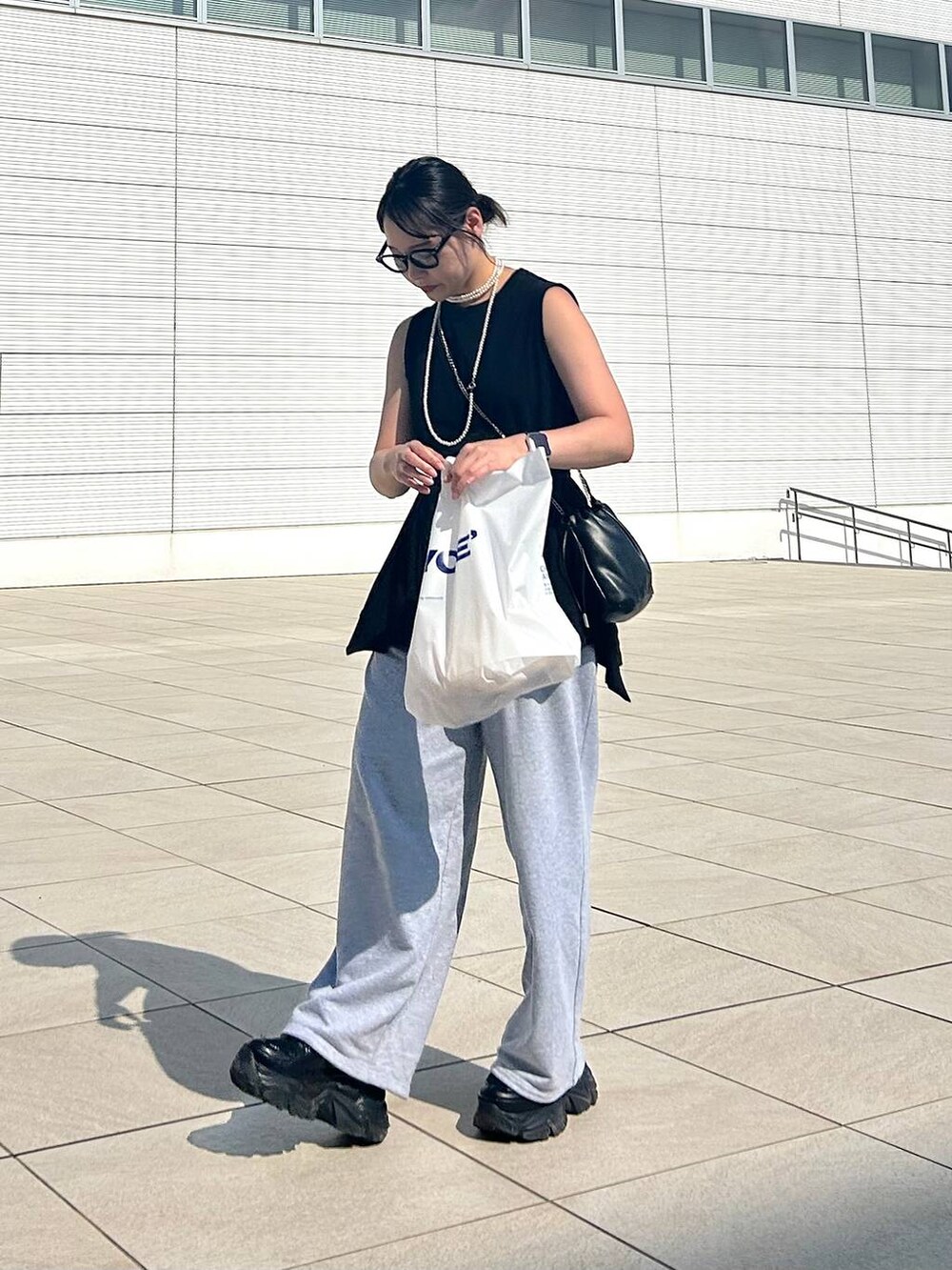 ブラック系のスニーカー、グレー系のスウェットパンツ、ブラック系のTシャツ/カットソーを着用したレディースの夏コーディネートの5枚目の写真