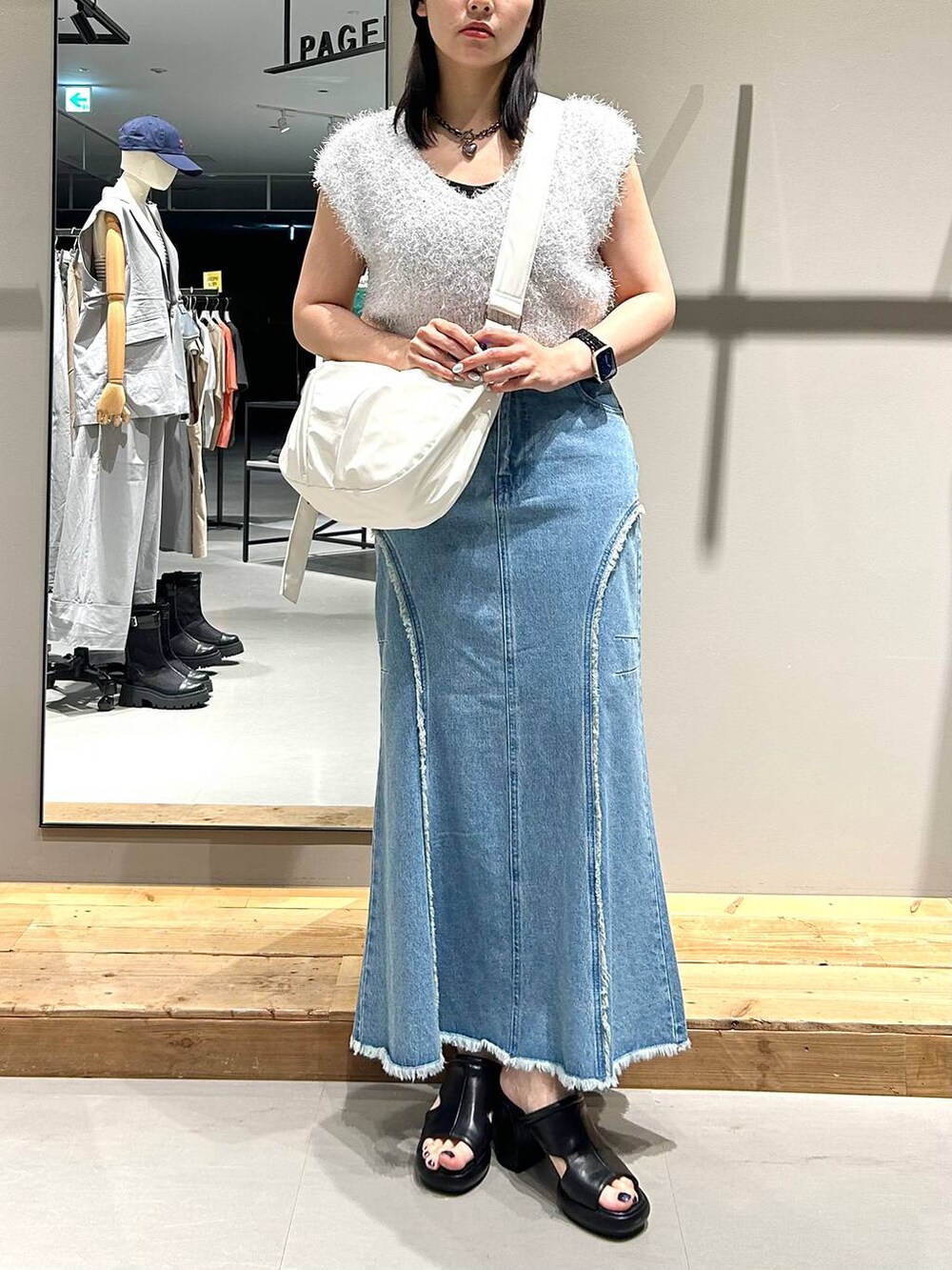 ホワイト系のベスト、ブルー系のデニムスカート、ブラック系のネックレスを着用したレディースの夏コーディネートの3枚目の写真