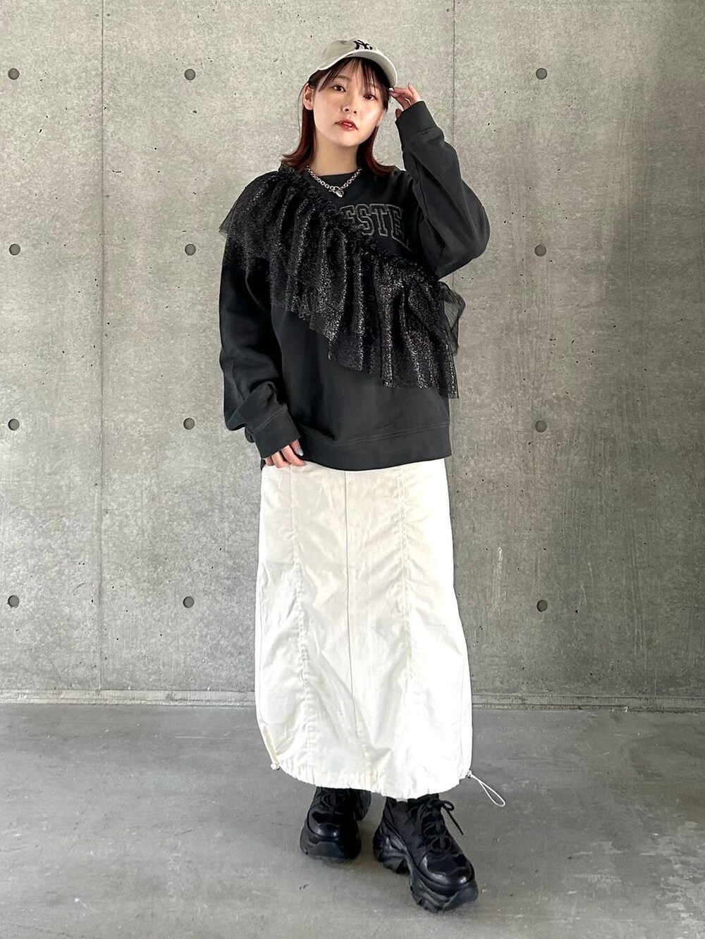 ブラック系のスニーカー、ホワイト系のスカート、ブラック系のスウェットを着用したレディースの春コーディネートの3枚目の写真