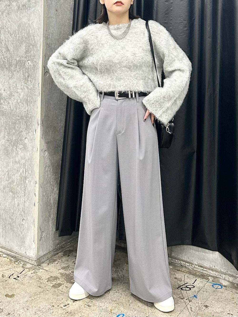 ホワイト系のスニーカー、グレー系のニット/セーター、ブラック系のベルトを着用したレディースの秋コーディネートの3枚目の写真