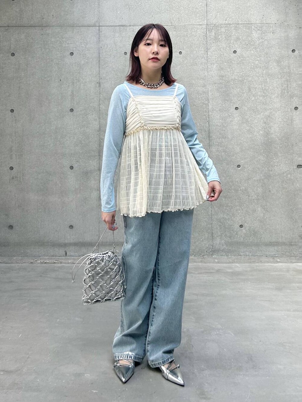 シルバー系のショルダーバッグ、ブルー系のデニムパンツ、ホワイト系のキャミソールを着用したレディースの春コーディネートの2枚目の写真