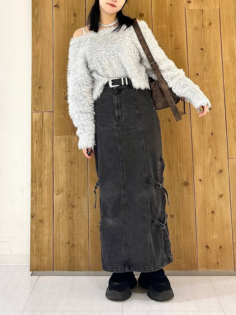 ブラウン系のショルダーバッグ、ブラック系のデニムスカート、ブラック系のスニーカーを着用したレディースの秋コーディネートの2枚目の写真