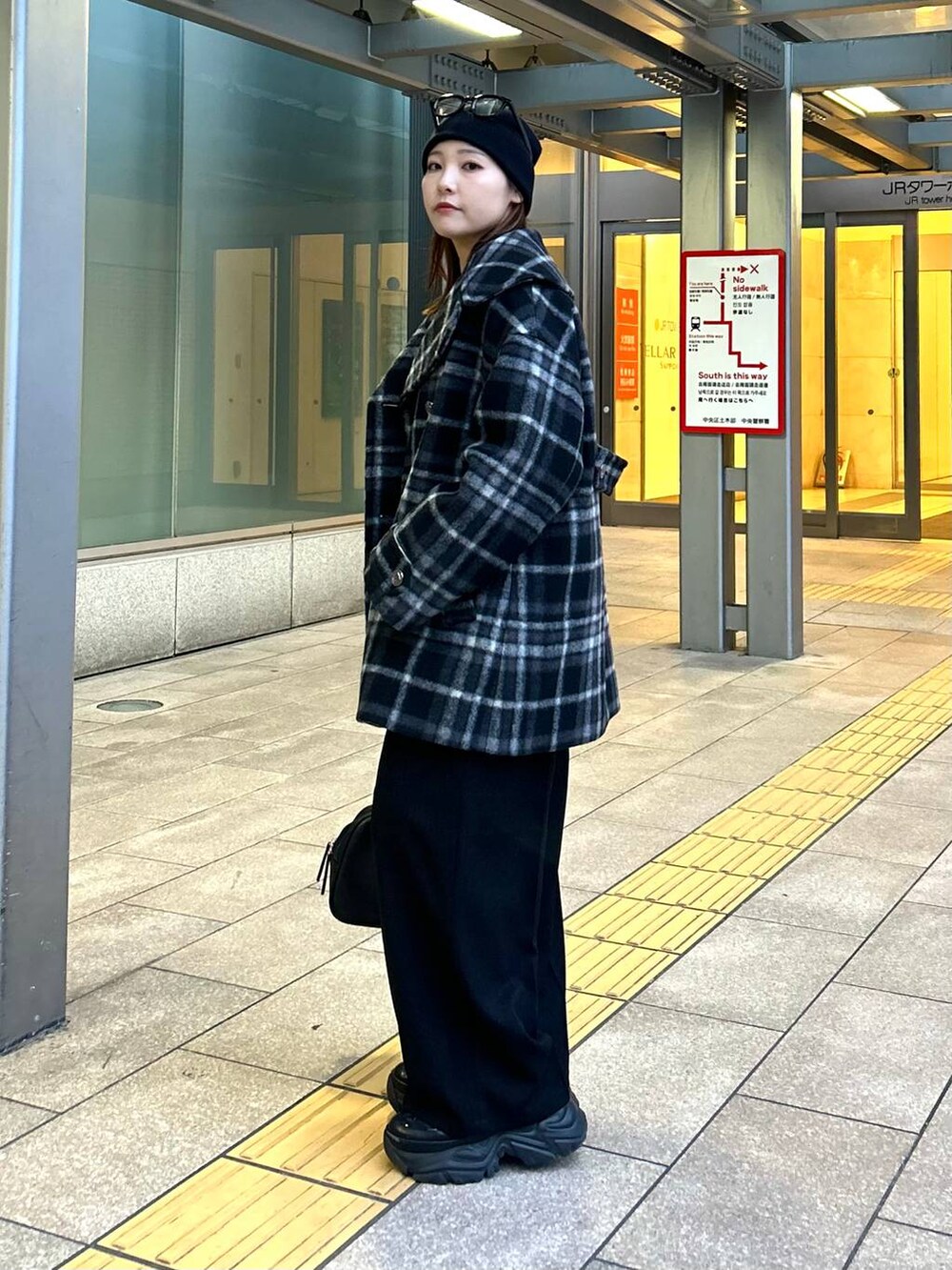 ブラック系のスニーカー、ブラック系のチェスターコート、ブラック系のボストンバッグを着用したレディースの秋コーディネートの3枚目の写真