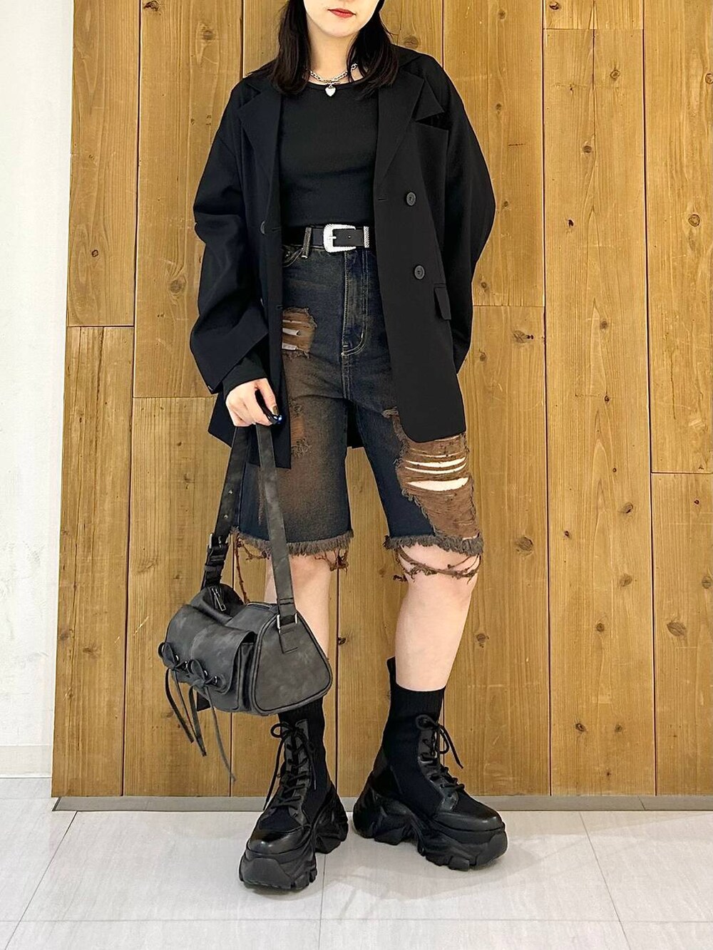 ブラック系のテーラードジャケット、ブラック系のショルダーバッグ、ブラック系のブーツを着用したレディースの秋コーディネートの3枚目の写真