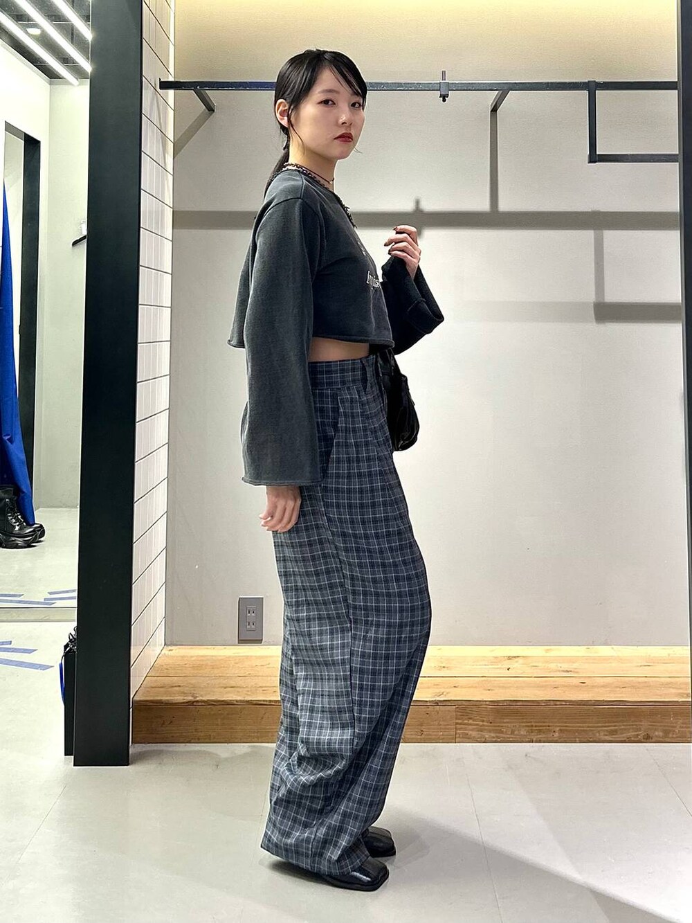 ブラック系のブーツ、グレー系のスラックス、ブラック系のハンドバッグを着用したレディースの秋コーディネートの4枚目の写真