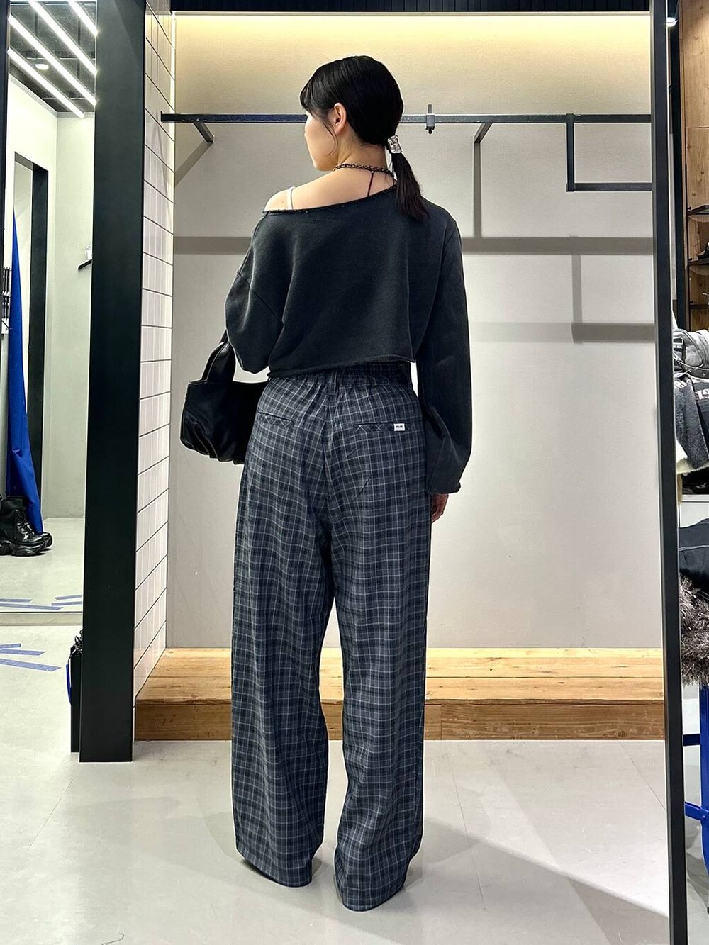 ブラック系のブーツ、グレー系のスラックス、ブラック系のハンドバッグを着用したレディースの秋コーディネートの5枚目の写真