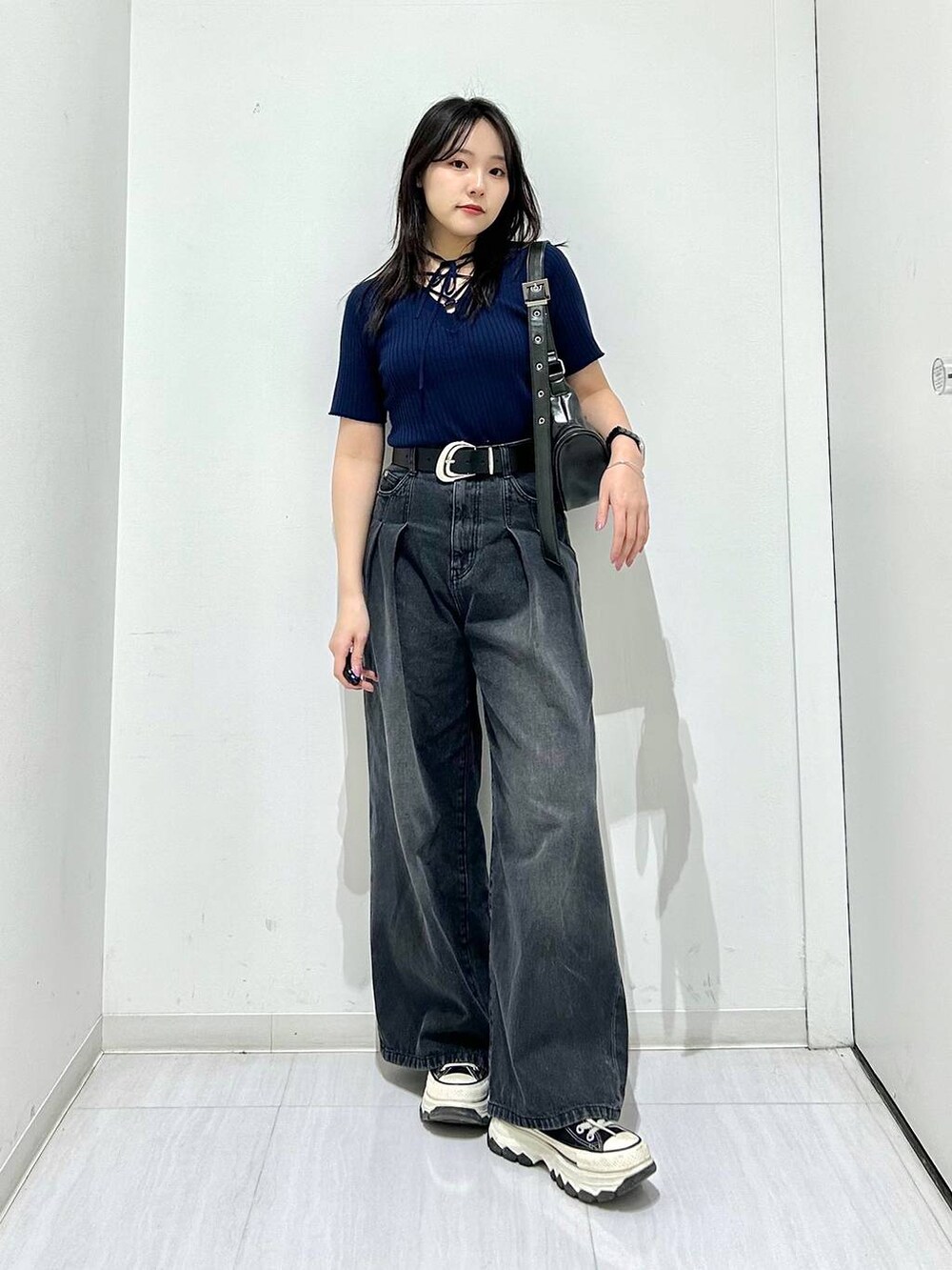 ブラック系のデニムパンツ、ブルー系のニット/セーター、ブラック系のベルトを着用したレディースの春コーディネートの2枚目の写真