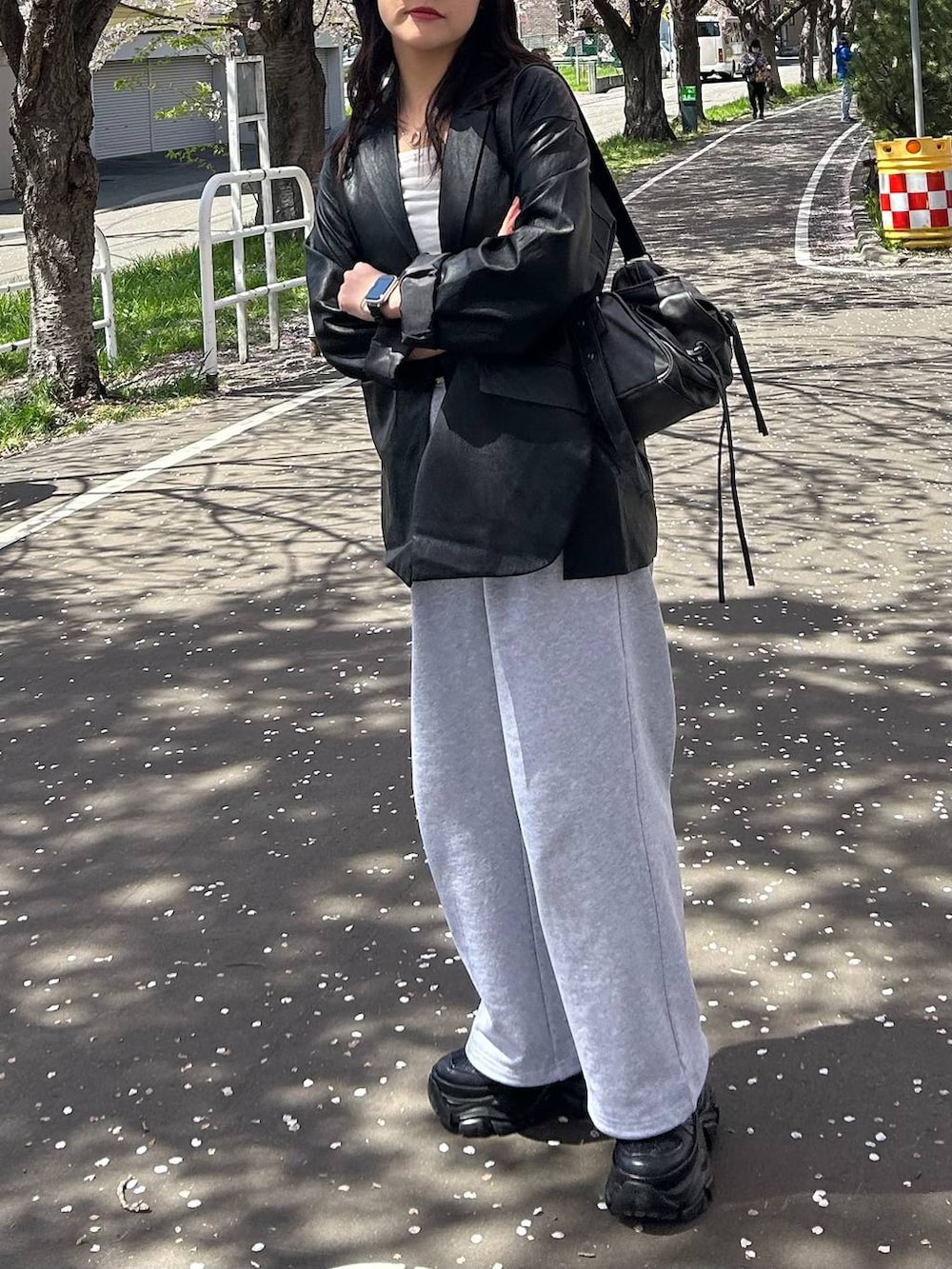 ブラック系のスニーカー、ブラック系のテーラードジャケット、グレー系のスウェットパンツを着用したレディースの春コーディネートの3枚目の写真