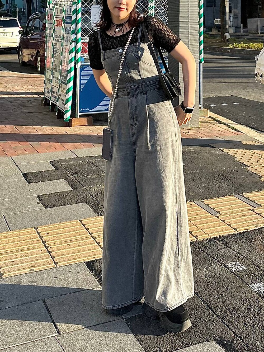 ブラック系のサロペット/オーバーオール、ブラック系のTシャツ/カットソー、ブラック系のハンドバッグを着用したレディースの夏コーディネートの3枚目の写真