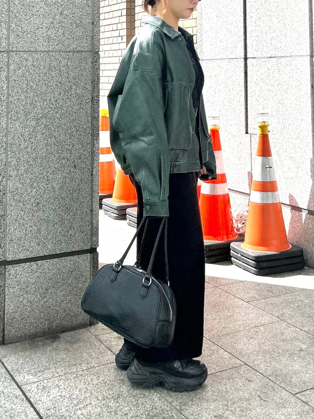 ブラック系のスニーカー、ブラック系のデニムパンツ、グリーン系のブルゾンを着用したレディースの秋コーディネートの5枚目の写真