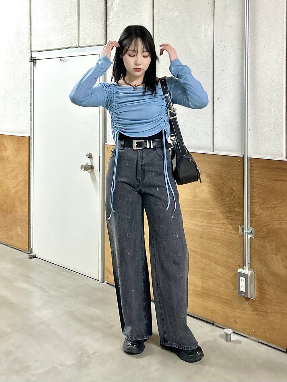 ブラック系のデニムパンツ、ブラック系のスニーカー、ブラック系のショルダーバッグを着用したレディースの春コーディネートの6枚目の写真