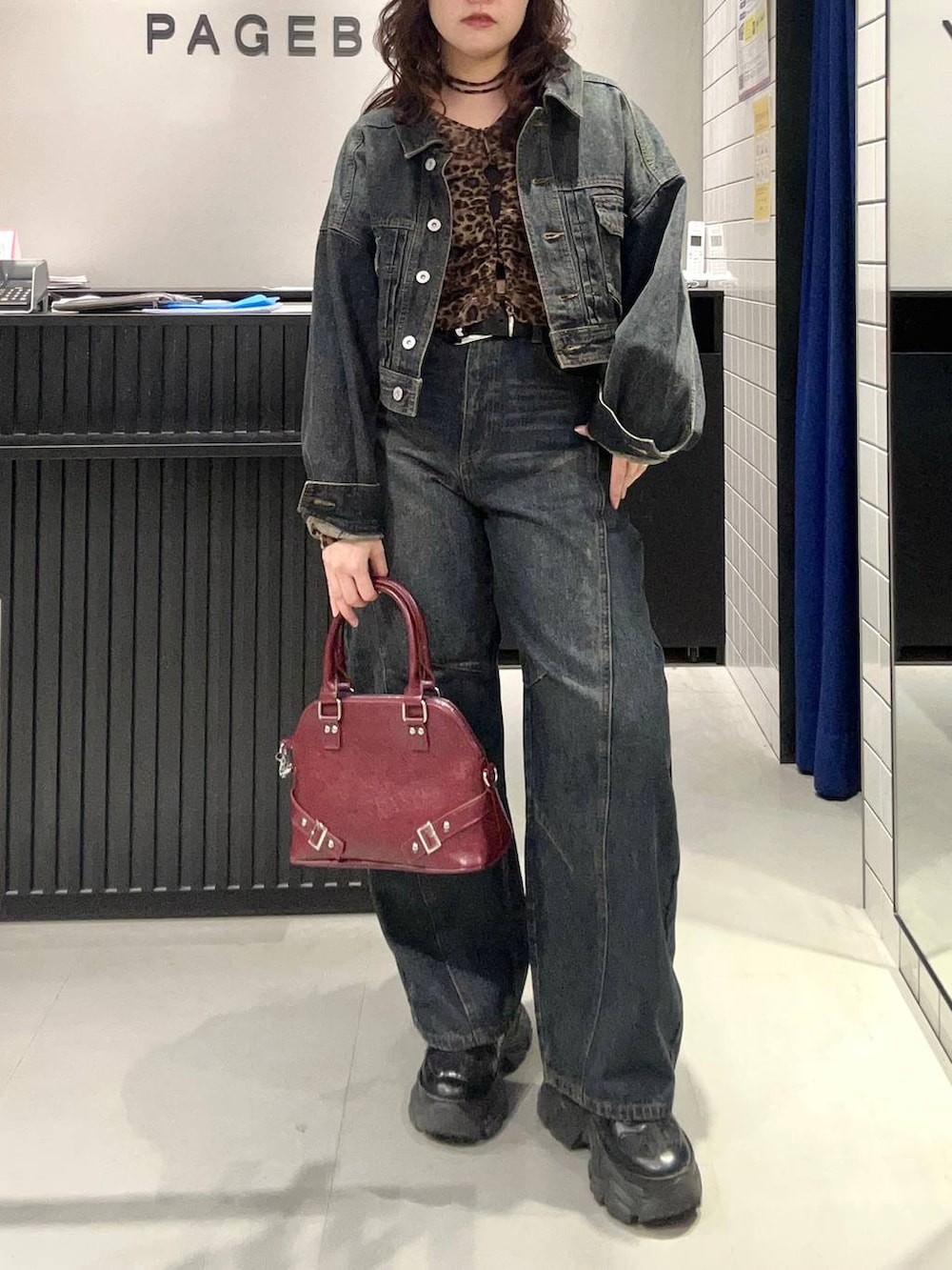 ブルー系のデニムパンツ、ブラック系のスニーカー、ブルー系のデニムジャケットを着用したレディースの秋コーディネートの2枚目の写真