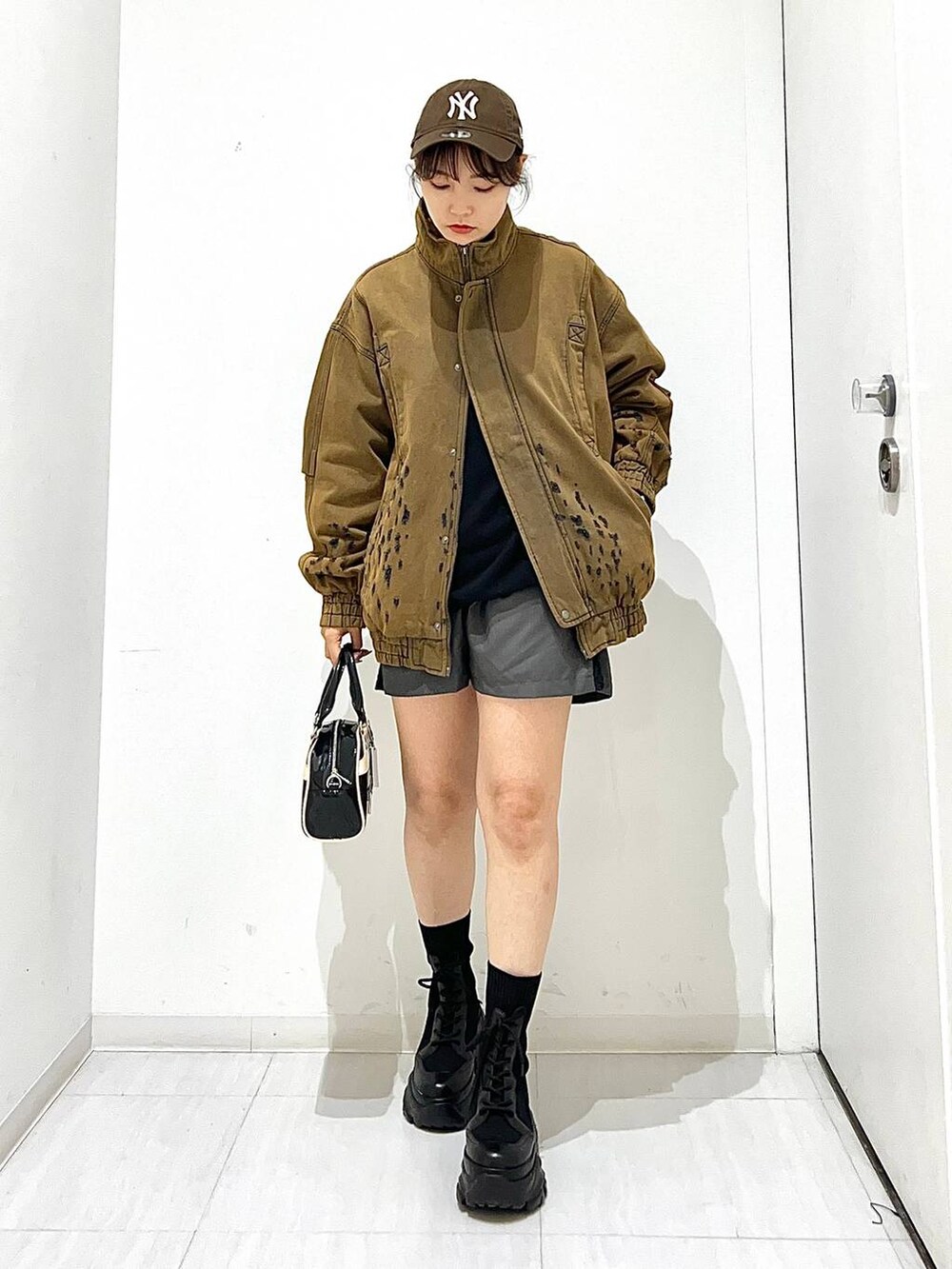 ブラック系のショルダーバッグ、ブラウン系のデニムジャケット、ブラック系のブーツを着用したレディースの秋コーディネートの2枚目の写真