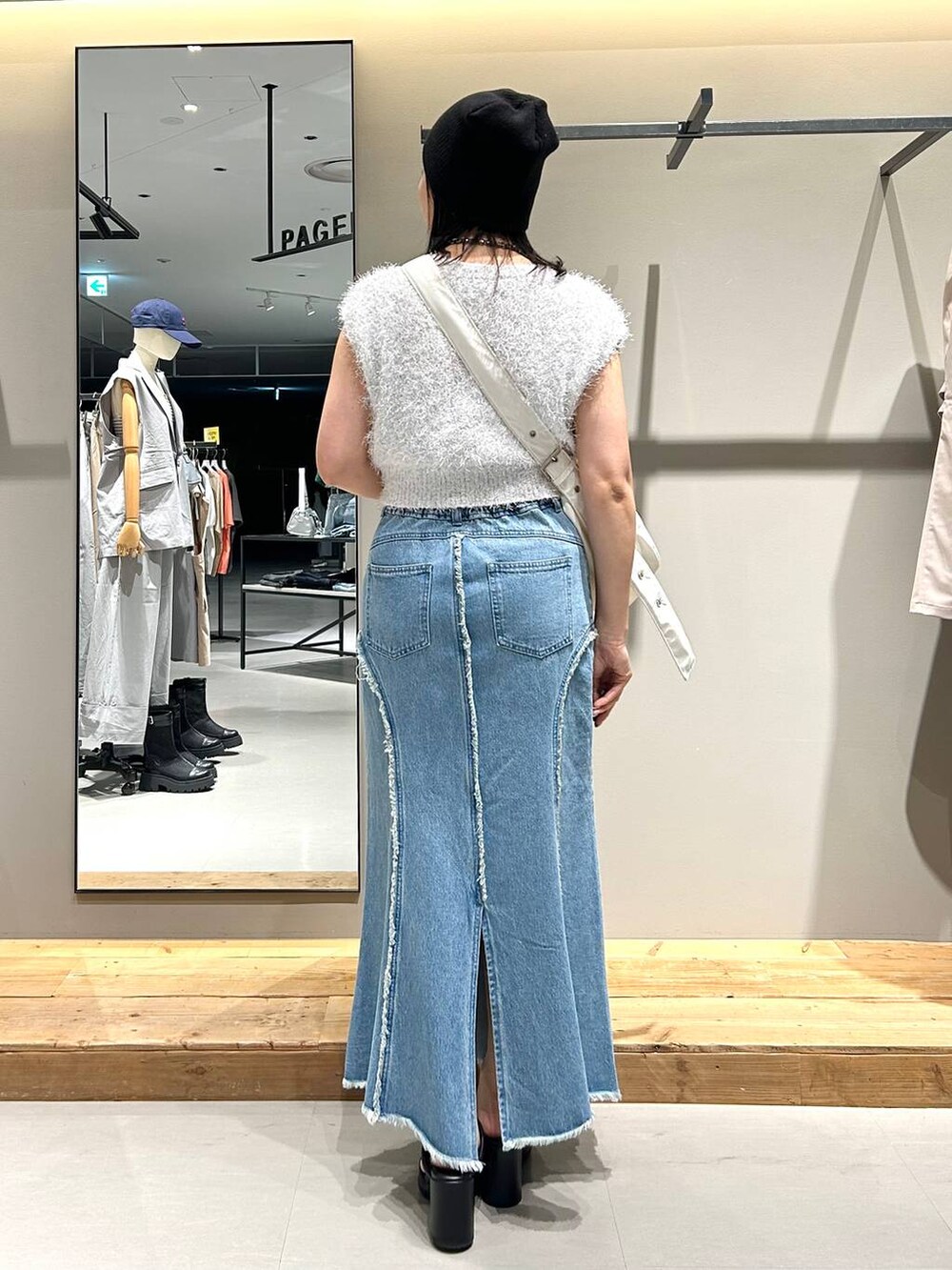 ホワイト系のベスト、ブルー系のデニムスカート、ブラック系のネックレスを着用したレディースの夏コーディネートの6枚目の写真