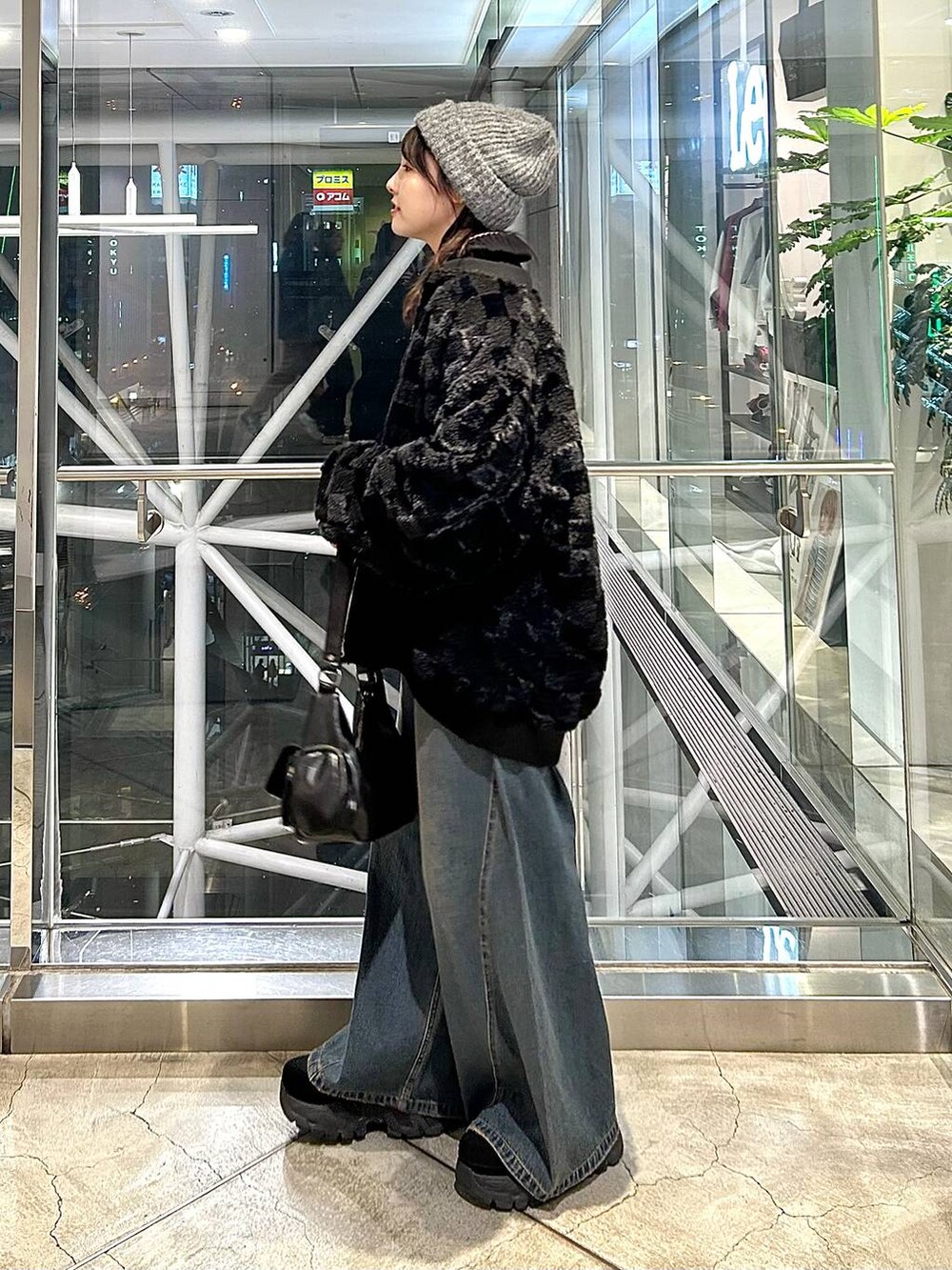 ブルー系のデニムパンツ、ブラック系のブルゾン、ブラック系のショルダーバッグを着用したレディースの秋コーディネートの5枚目の写真